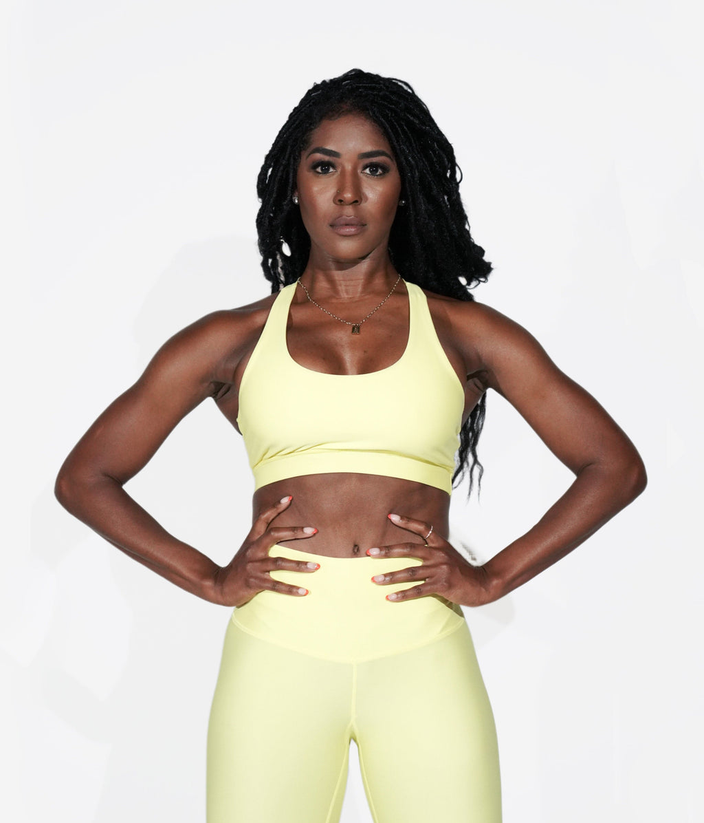 A woman wearing the yellow Daybreak Bra from NoorFit.