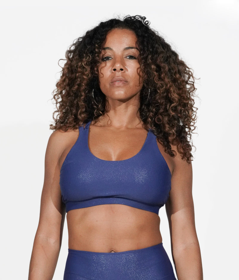 A model with black curly hair wears the Galaxy Strappy Back Bra with matching leggings. 