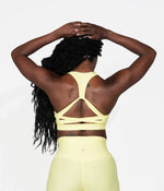 A woman wearing the yellow Daybreak Bra from NoorFit.