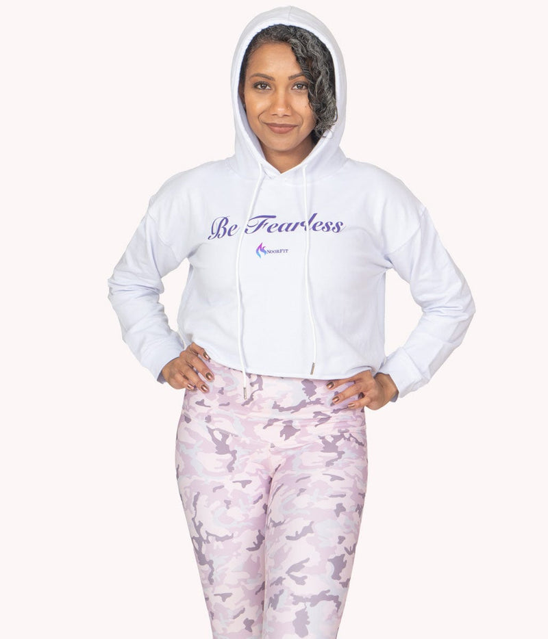 A model with her hands on her hip wearing the Be Fearless Crop Hoodie with the hood pulled up.