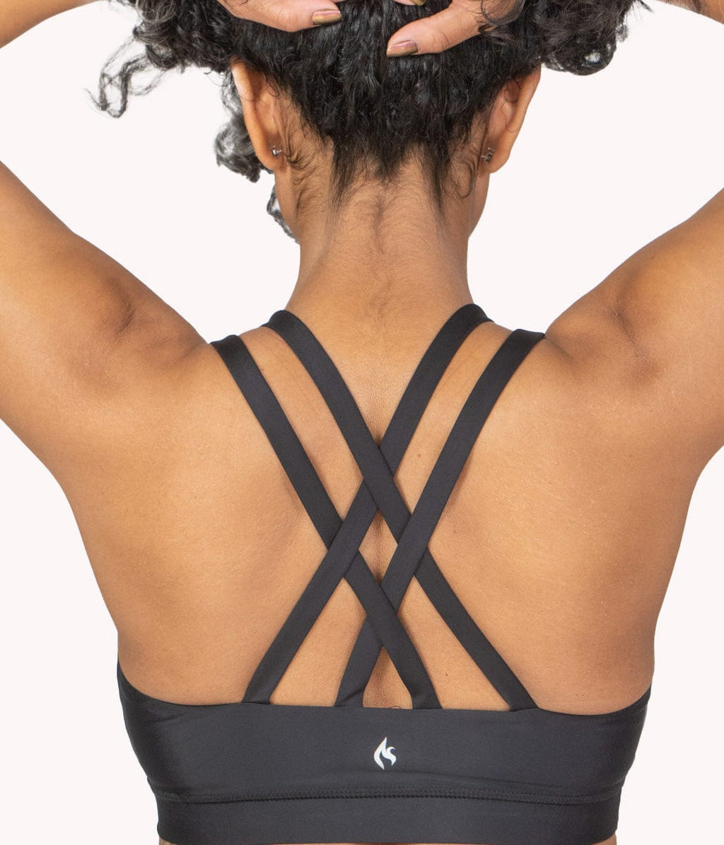 A model showing the Criss Cross Strappy Back design of our sports bra in obsidian. 
